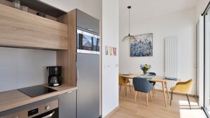 Une cuisine moderne équipée d’un four encastré, d’une machine à café et d’un coin repas avec une table et des chaises.