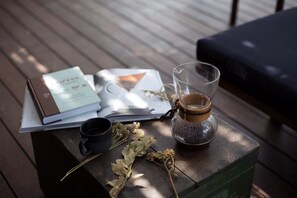 A wooden table with a laptop, a glass coffee pot, a black mug, and dried leaves. - Double A House (Pererenan)