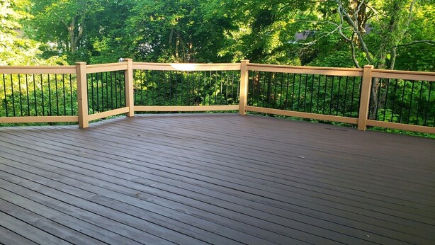 A wooden deck with a railing, surrounded by lush greenery. - Spacious Private Home with Large Deck  (South Haven)