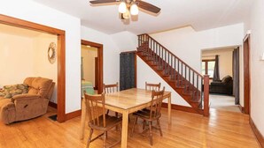 A spacious living room with a wooden dining table and chairs, a ceiling fan, and a staircase leading to another level. - Spacious Private Home with Large Deck  (South Haven)