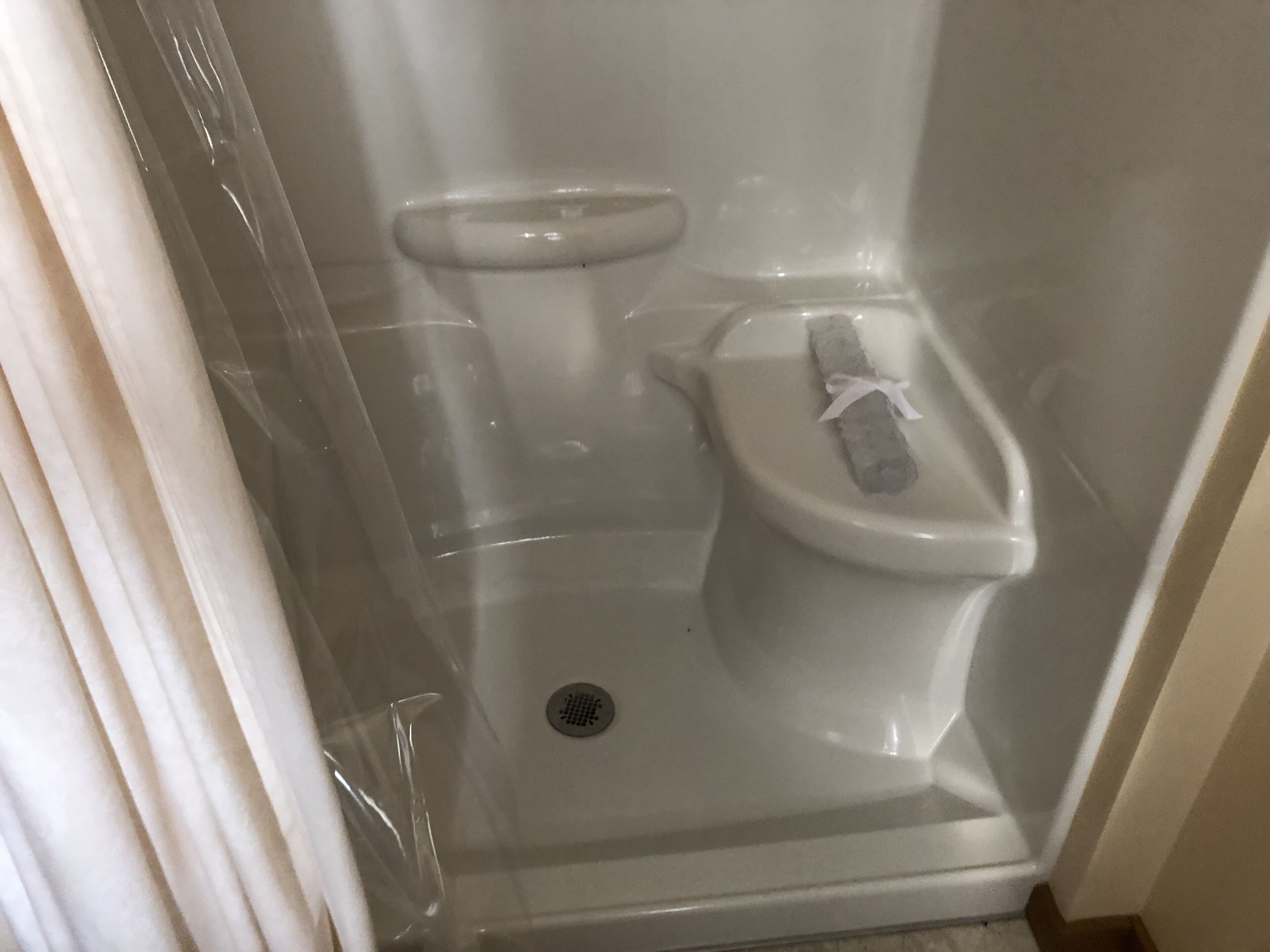 Une petite salle de bain fermée, comprenant des toilettes, un espace douche et un drain.