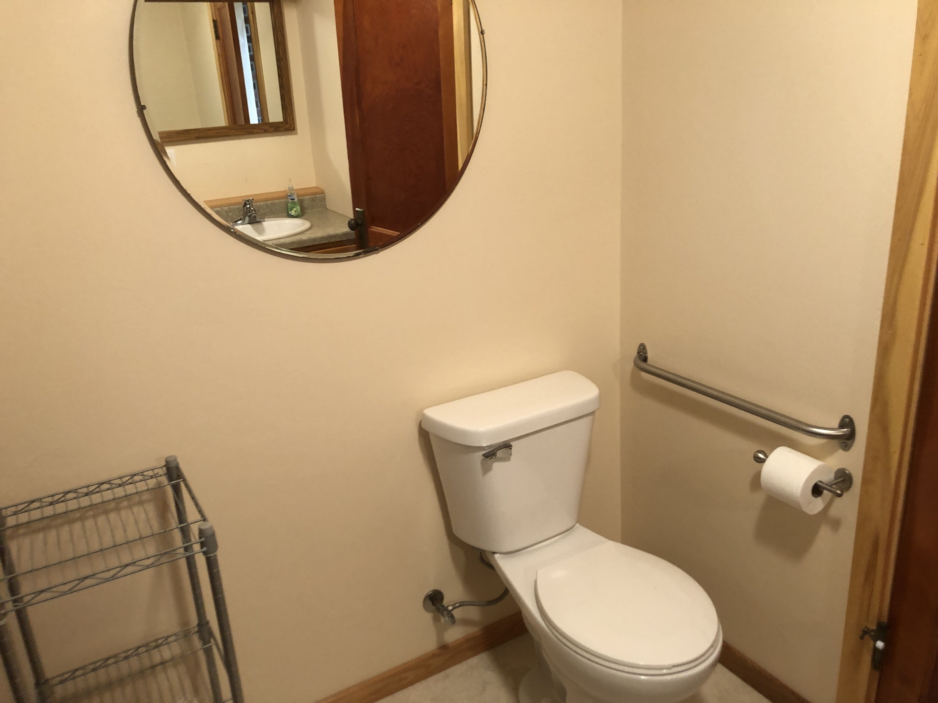 Un baño pequeño con inodoro, baranda, espejo y perchero.