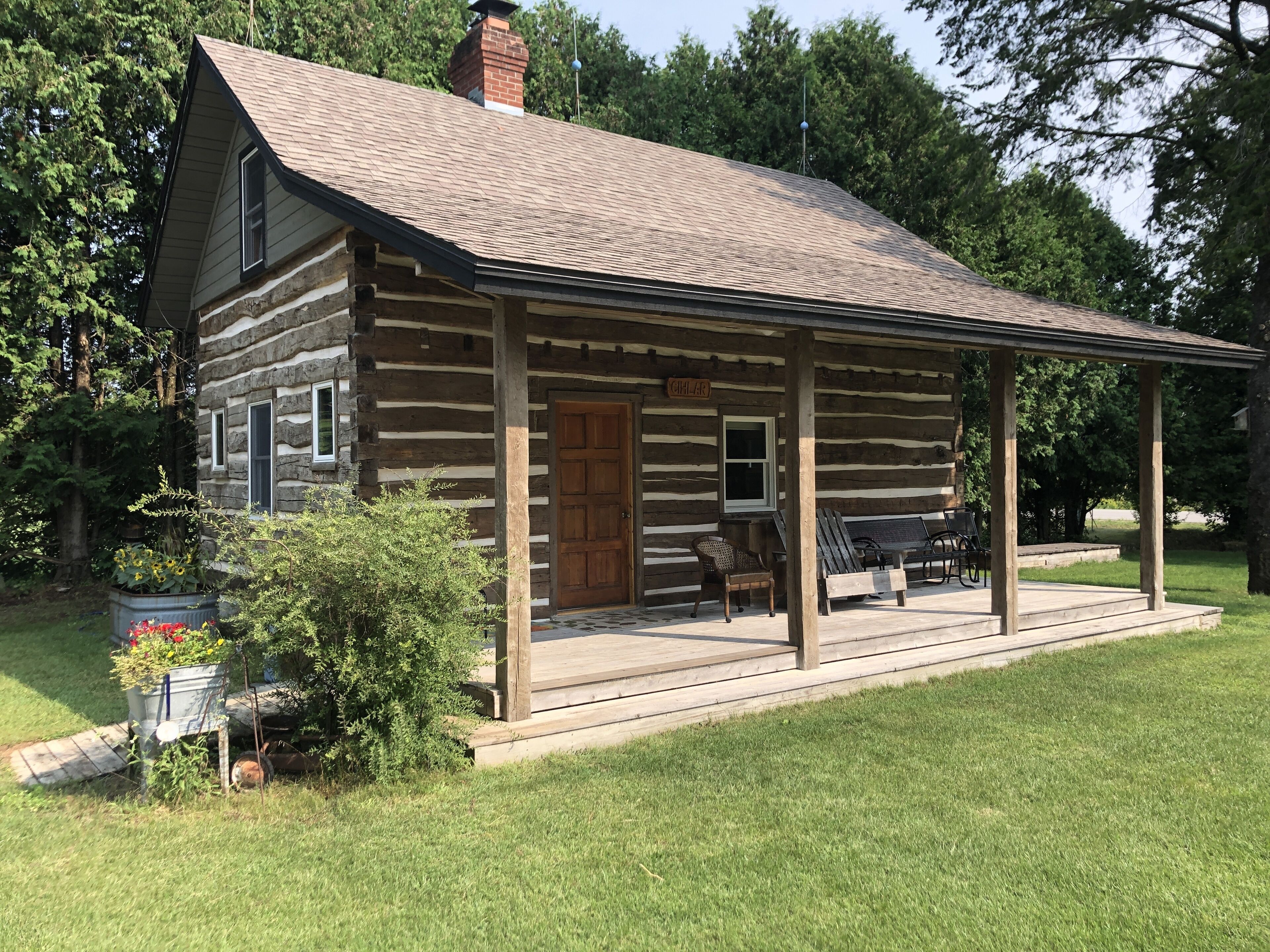Une cabane rustique en rondins de bois, dotée d’un porche, d’une cheminée et d’une enseigne sur laquelle on peut lire « CHILLY AR ».