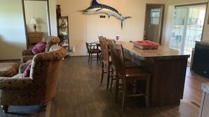 A dining area with a wooden table and chairs, a fish mural on the wall, and a kitchen area with a refrigerator and sink. - Aggie Game day in the country outside of College Station!  (Cameron)