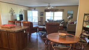 A spacious living area with a wooden dining table, chairs, and a kitchen area with a counter and cabinets. - Aggie Game day in the country outside of College Station!  (Cameron)