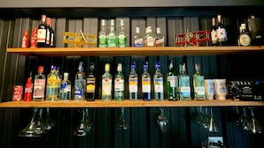Un bar con numerose scaffalature piene di bottiglie di liquori e bicchieri.