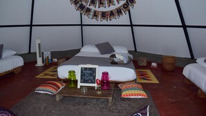 Una camera accogliente con un letto, cuscini, un tavolino con un cartello e uno striscione con la scritta 'Feliz Cumpleaños'.