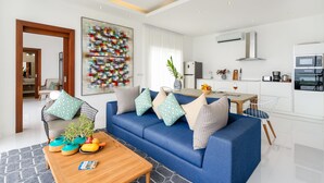 Uma sala de estar moderna com um sofá azul, uma mesa de centro de madeira e uma pintura abstrata colorida.