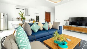 Uma sala de estar moderna com um sofá azul, mesa de centro de madeira e uma televisão de tela plana.