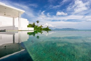 A modern infinity pool with clear water reflecting the sky and surrounding greenery. - Villa Claire (Koh Samui)