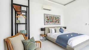 Quarto moderno com cama, cadeira, mesinha de cabeceira e ar condicionado fixado na parede.