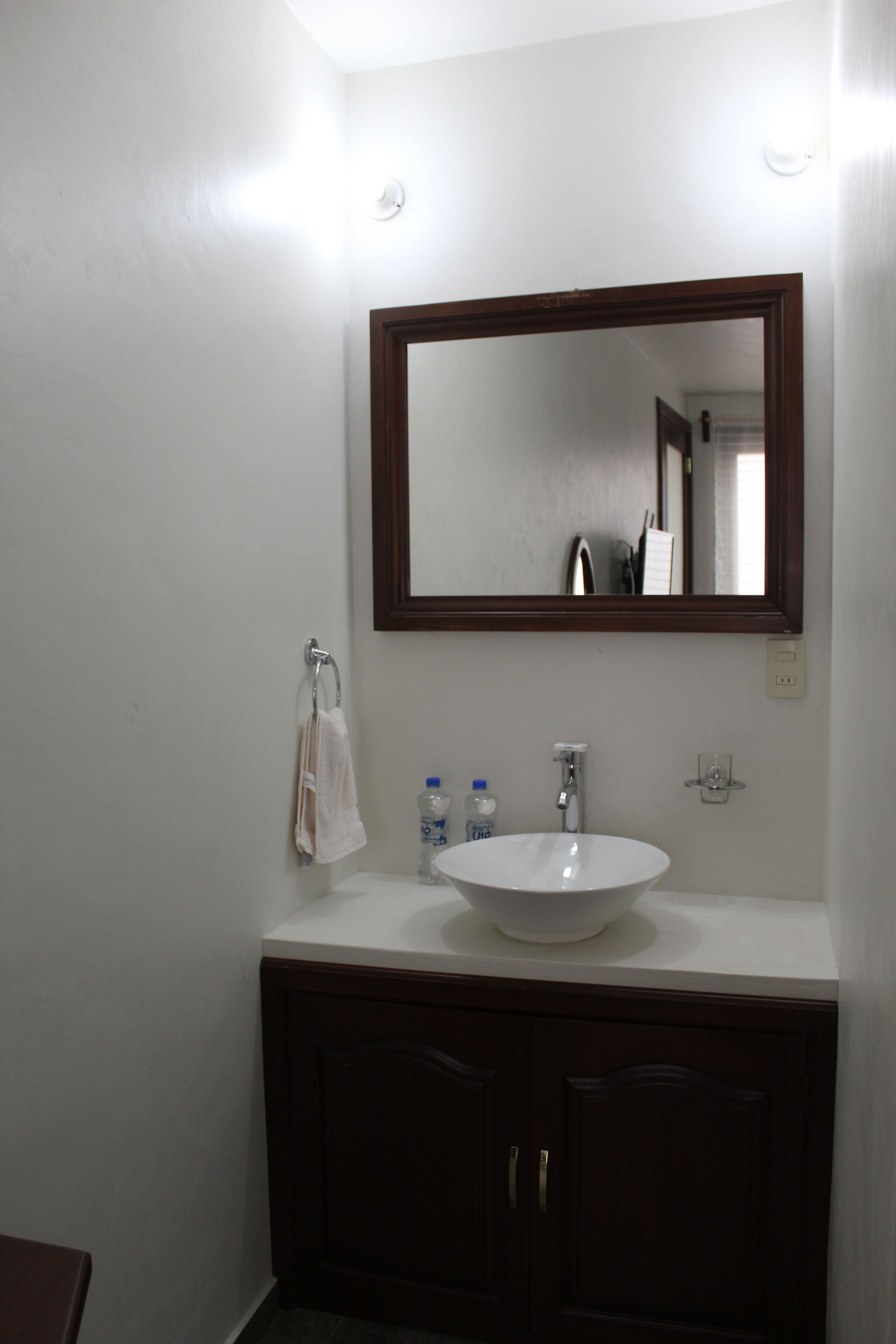 A bathroom with a white sink, dark wooden cabinets, and a large mirror.
