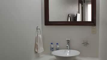 A bathroom with a white sink, dark wooden cabinets, and a large mirror.