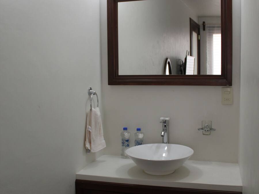 A bathroom with a white sink, dark wooden cabinets, and a large mirror.
