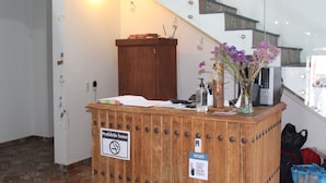 A reception desk with a sign prohibiting smoking, a visitor sign, and a vase with purple flowers.