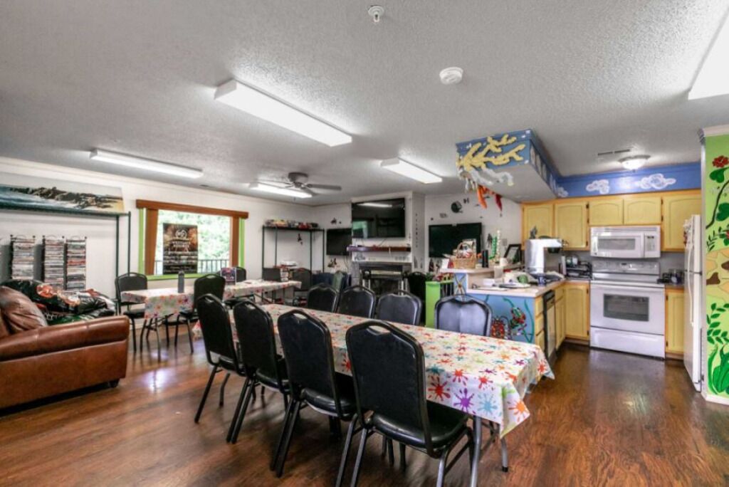 A spacious living room with a dining area, kitchen, and a large window.