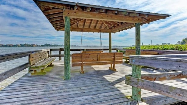 A wooden pier with a covered seating area and a bench. - The Sea Grape, end unit, walk to beach (Bradenton Beach)