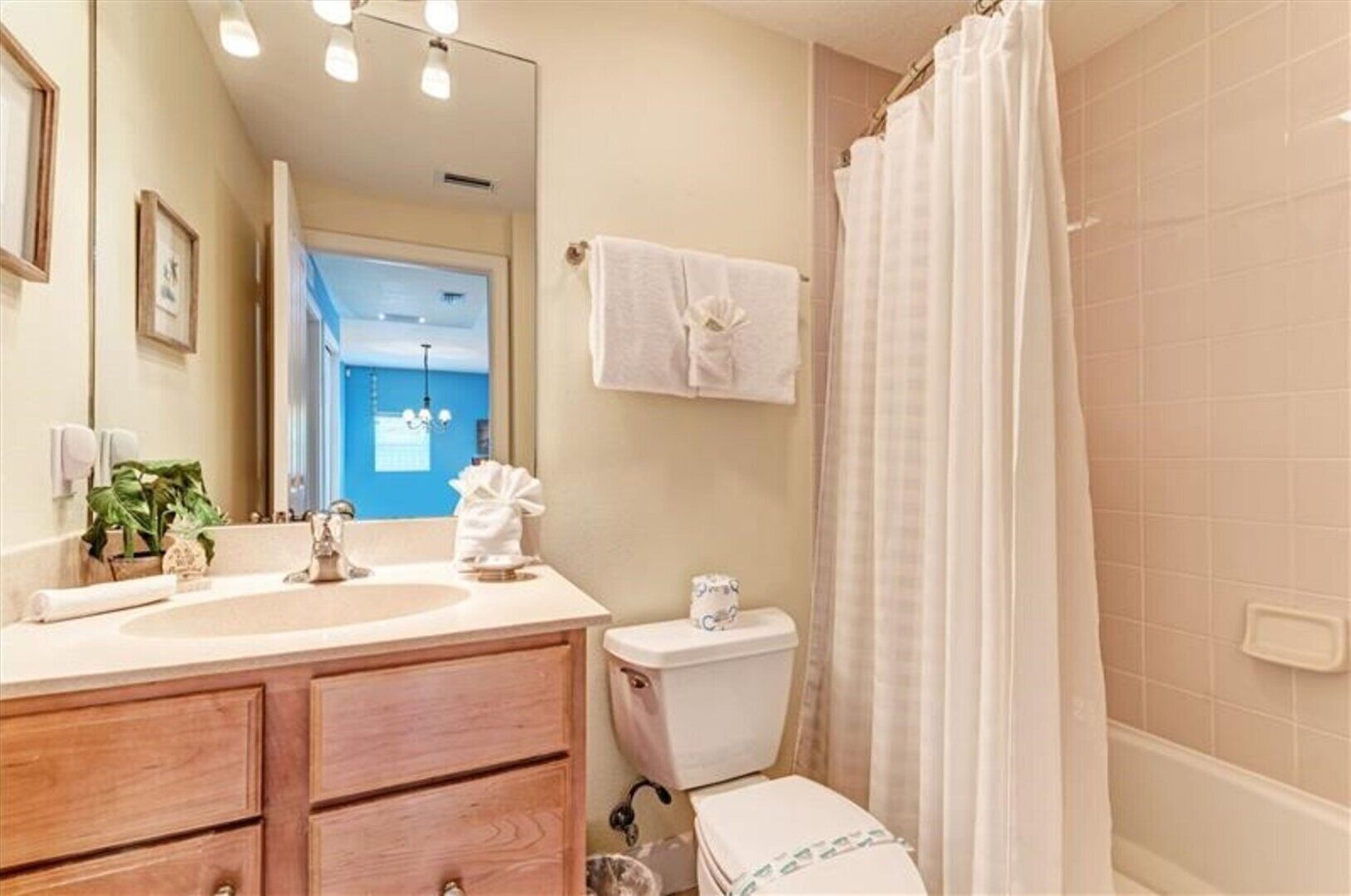 A bathroom with a sink, mirror, toilet, and shower curtain.