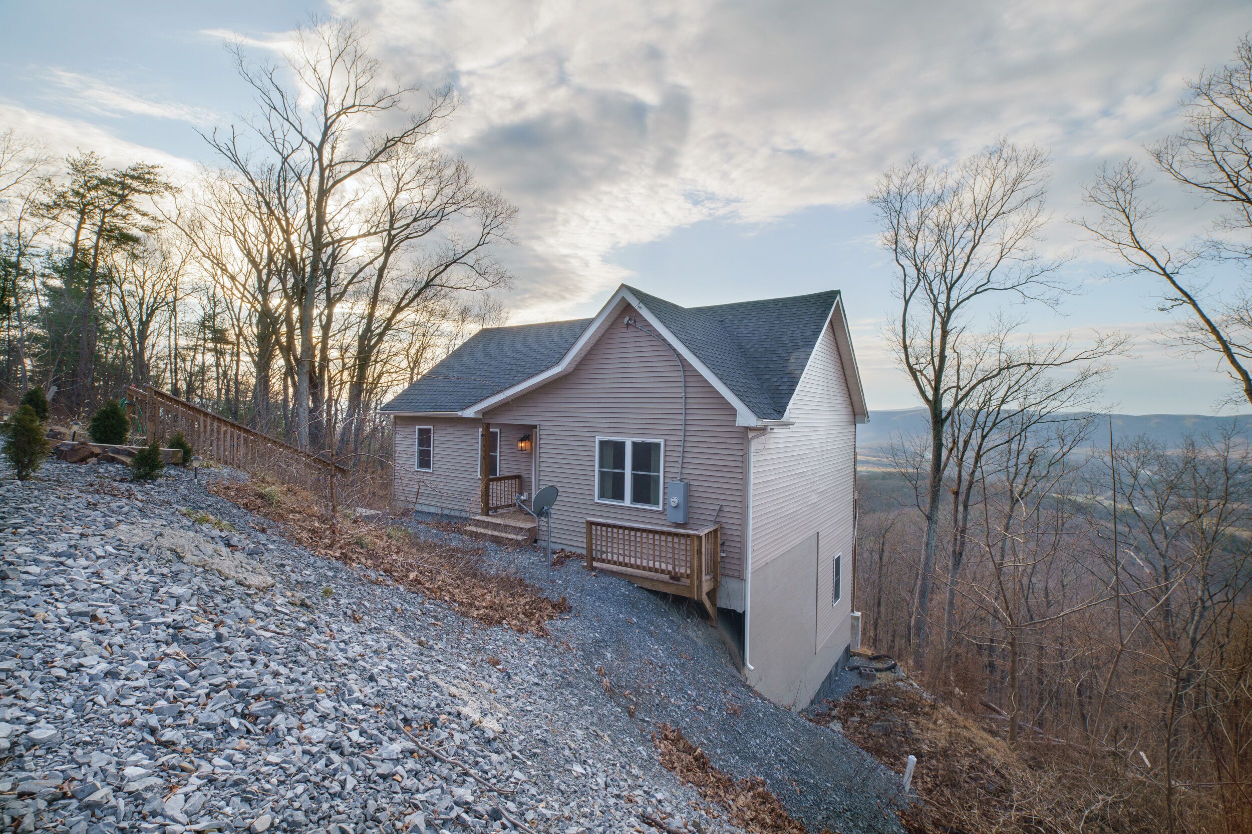 A single-story house with a sloped roof, a front porch, and a gravel driveway.