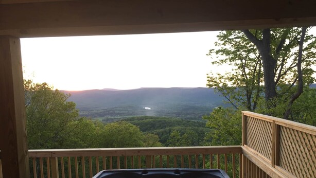 A hot tub on a wooden deck with a view of a forest and mountains. -  Large-Group Cabin near Luray · Sleeps 12 · Hot Tub & Mountain Views (Rileyville)