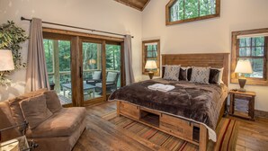 A bedroom with a large bed, wooden headboard, and a view of the outdoors through a sliding glass door.