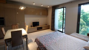 A modern bedroom with a large bed, a TV, a dining area, and a balcony with a view of greenery. - Modern lux flat( studio) by Wawel Castle  (Krakow)