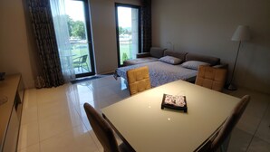 A modern hotel room with a bed, a sofa, a dining table, and a balcony with a view of the outdoors. - Modern lux flat( studio) by Wawel Castle  (Krakow)