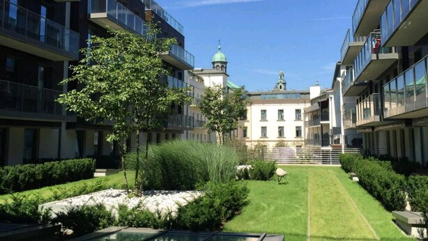 A modern building with balconies, a central courtyard with a lawn, and a church in the background. - Modern lux flat( studio) by Wawel Castle  (Krakow)