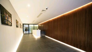 A modern interior with a reception desk, a wooden accent wall, and a tiled floor. - Modern lux flat( studio) by Wawel Castle  (Krakow)