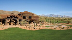 A large, rustic building with a prominent porch and multiple windows, surrounded by a well-maintained lawn and desert landscaping. - Dove Mountain Retreat - Private pool (Marana)