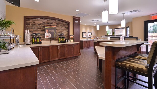 A modern kitchen with a central island, wooden cabinets, and a stone accent wall.