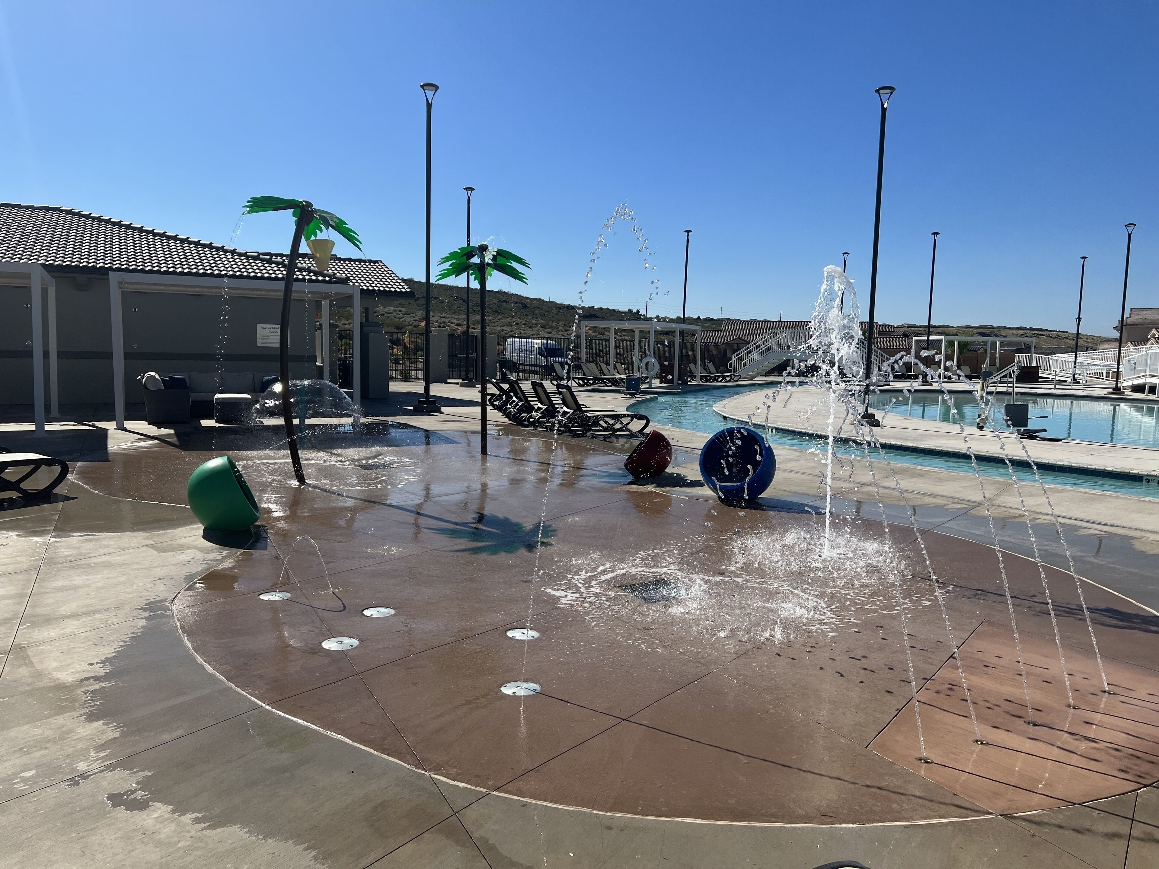 Zona de piscina con fuentes, sillas de descanso y un área de estar cubierta.