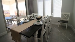 Un coin repas avec une table en bois foncé, des chaises blanches et un lustre.