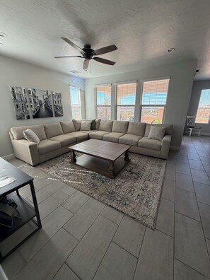 A living room with a sectional sofa, a coffee table, and a ceiling fan. - Poolside Luxury Home - 5BR 4BA (Washington)