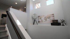 Un escalier menant à un palier où se trouvent une carte du monde, une boussole et une valise posée sur une étagère.