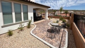 Une terrasse dotée d’un motif en briques incurvé, de mobilier d’extérieur et offrant une vue sur un quartier résidentiel.