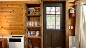 Een houten interieur met een deur, een boekenkast en een brandblusser.