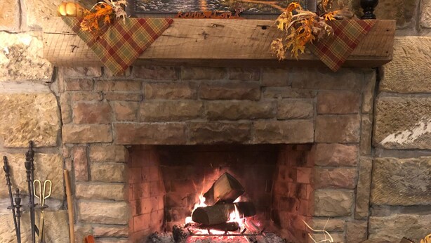 Una habitación acogedora con chimenea, una manta y una mesa de madera con hojas otoñales.