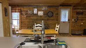 Una cocina con paredes de madera, un lavabo y una mesa de comedor con sillas.