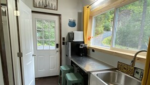 A compact kitchen with a window, a microwave, a sink, and a refrigerator.