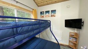 A bunk bed room with a window, a mounted TV, and a wooden shelf with a license plate.