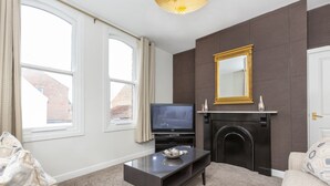 A living room with a fireplace, television, and a large window.