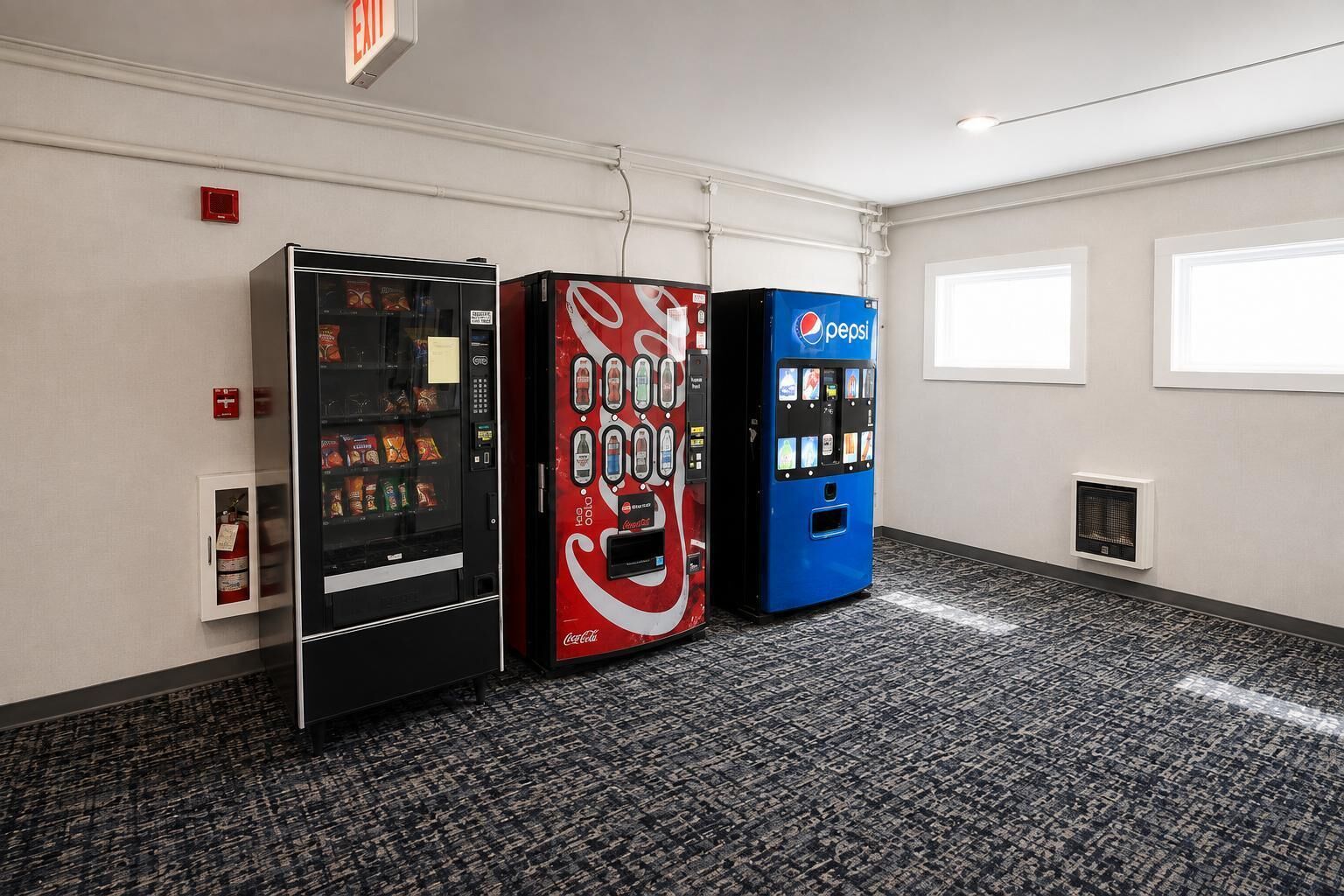 A room with three vending machines, a fire alarm, and a window.