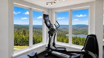 Een fitnessruimte met loopband, hometrainer en elliptische machine, met grote ramen en een prachtig uitzicht.