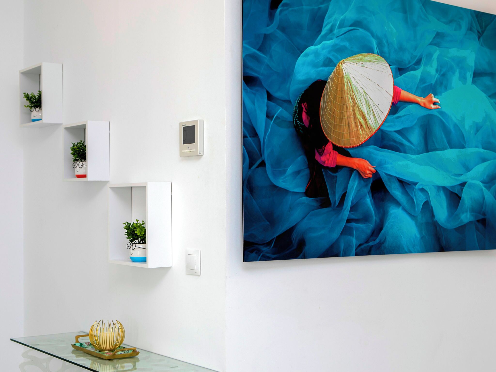 A modern interior with a large abstract painting, white shelving units, and a glass table with decorative items.