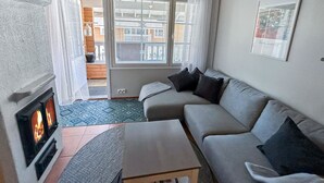 Una sala de estar con sofá, una mesita, chimenea y vistas a través de una ventana.