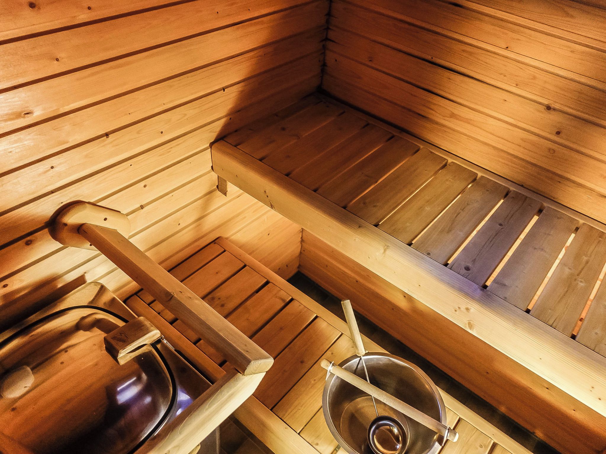 Et sauna-rum med træbænke og en stålbadekar.