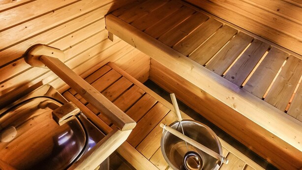 Una sala de sauna con bancos de madera y ducha de vapor.