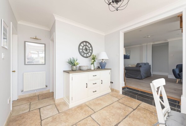 A modern living room with a white cabinet, a round wall clock, and a grey sofa.