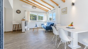 A modern living room with a wooden ceiling, a white dining table, and a blue sofa. - Villa Likva - Two Bedroom Villa with Private Pool and Hot Tub (Sutivan)